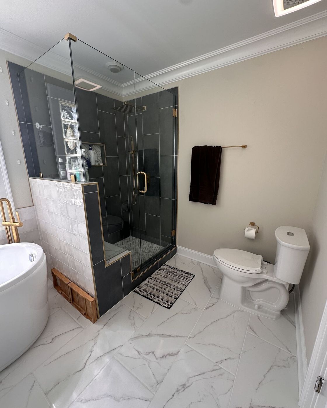 A frameless glass shower with charcoal tile and a built-in bench